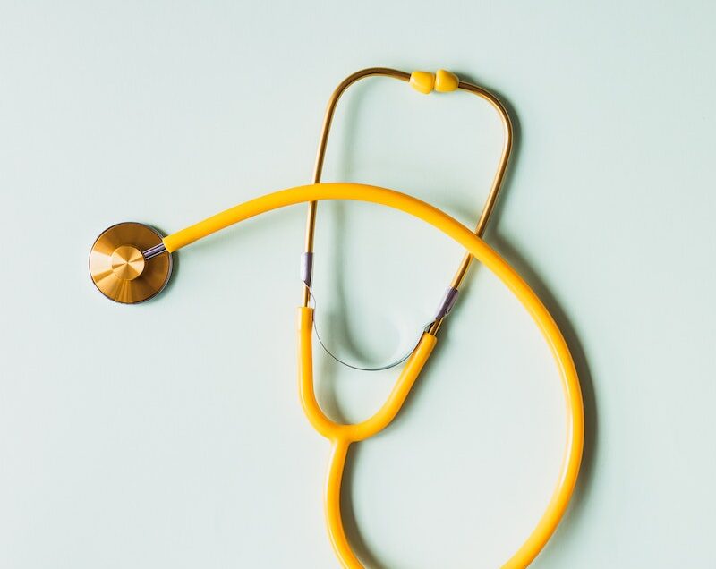 Top view of yellow medical stethoscope placed on white surface during coronavirus pandemic