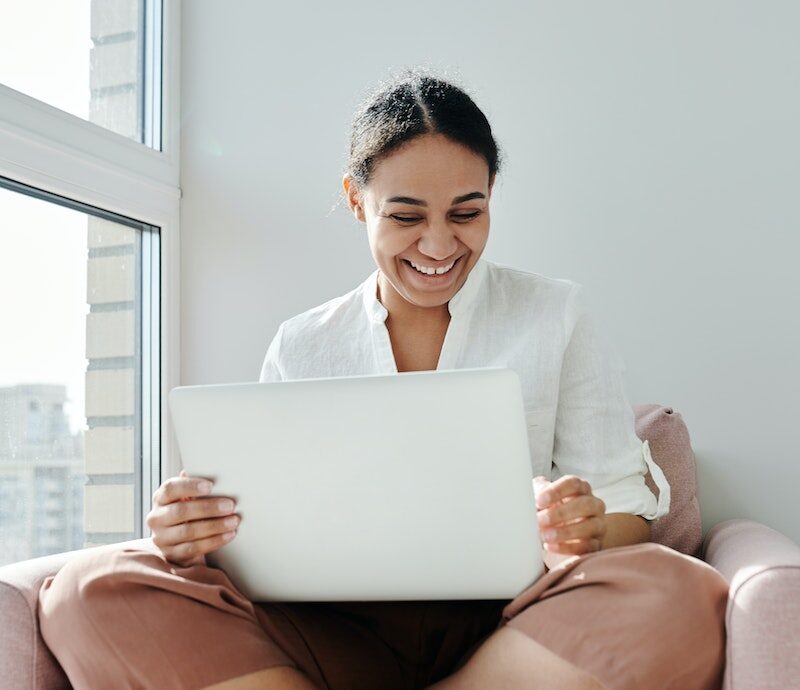 Woman Sitting on an Armchair while Working on a Laptop