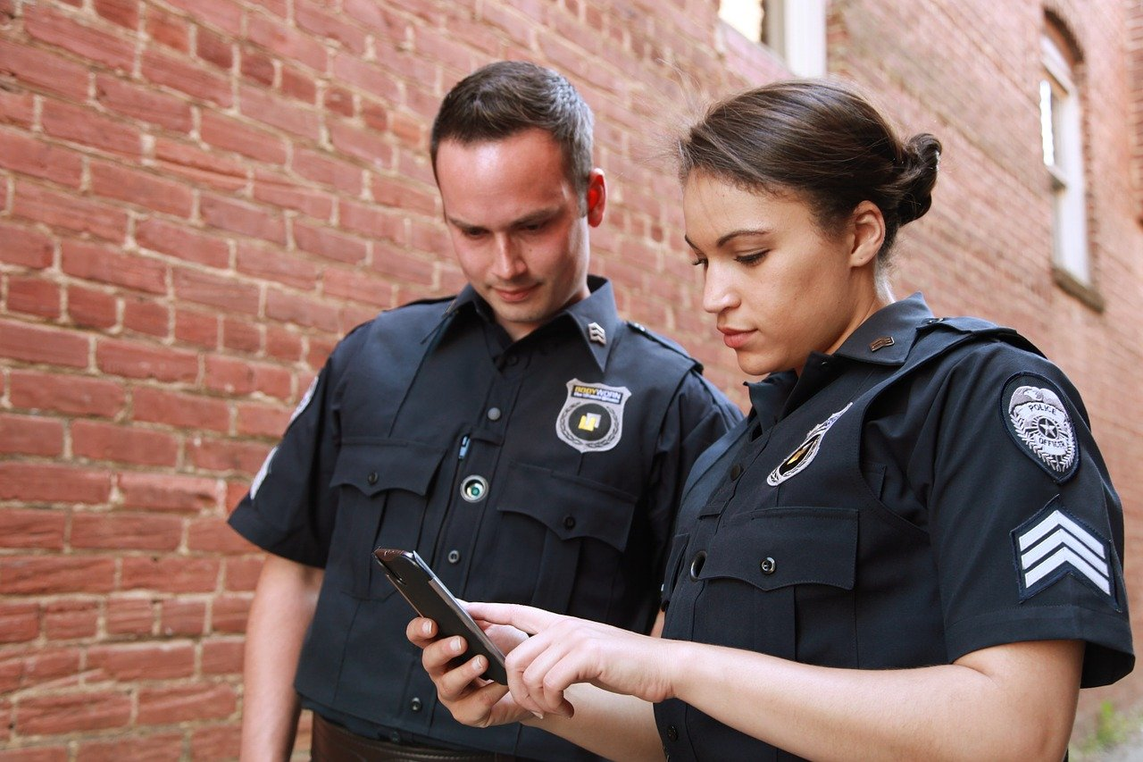 A policeman and a policewoman checking a cell phone to track coordinates during a security operation