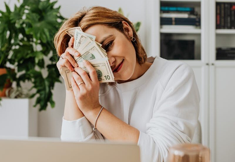 Woman Sitting in Front of Her Laptop and Holding a Lot of Cash 