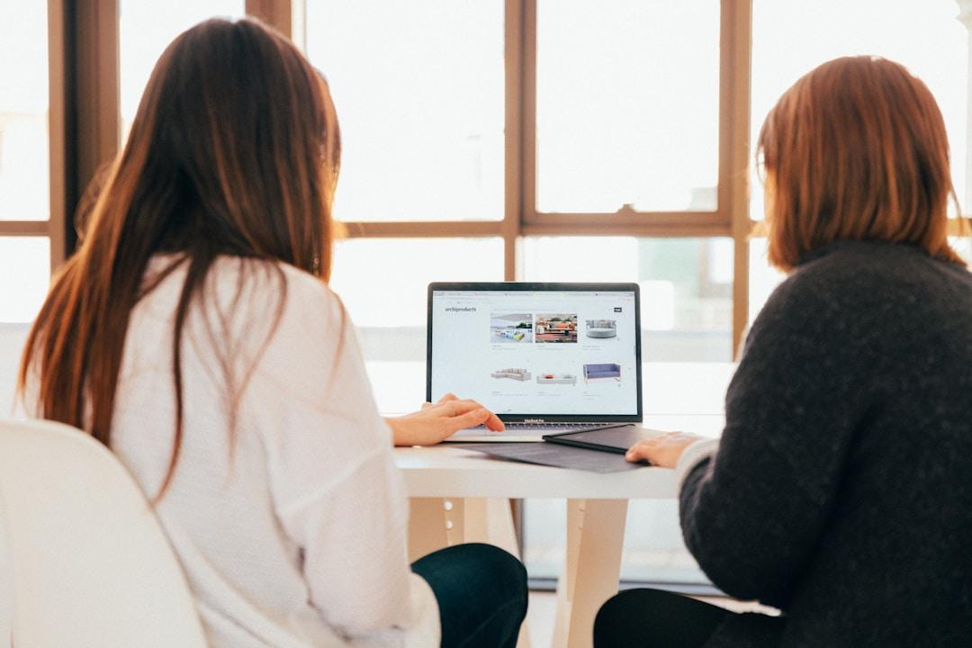 Two women seated side by side, collaboratively exploring 'examples of federated search' on a laptop screen.