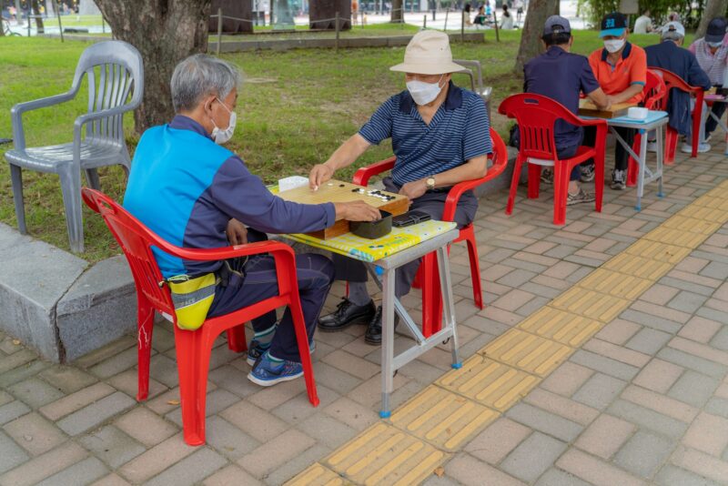 man in blue polo shirt sitting on red plastic chair